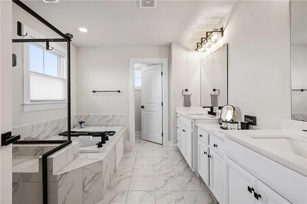 a bathroom with a tub sink vanity and mirror