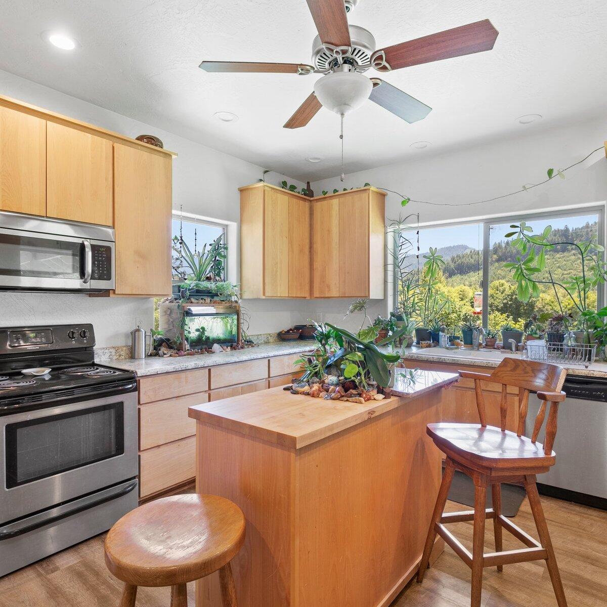 1104 Upper Cow Creek Road Azalea, OR 97410 - Photo 37 of 77 a kitchen with stainless steel appliances a dining table chairs wooden floor and a chandelier