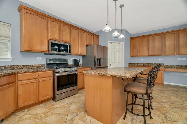 a kitchen with stainless steel appliances granite countertop a stove top oven a sink dishwasher a dining table and chairs with wooden floor