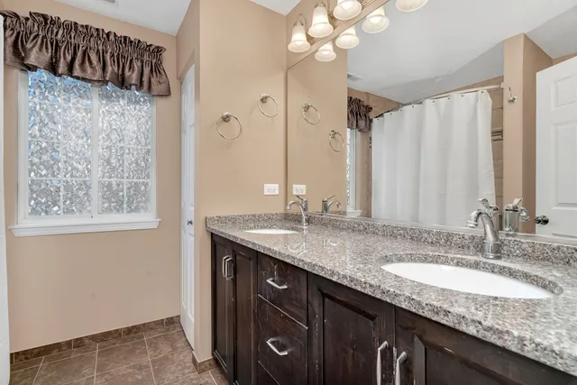 a bathroom with a granite countertop sink a mirror and a shower