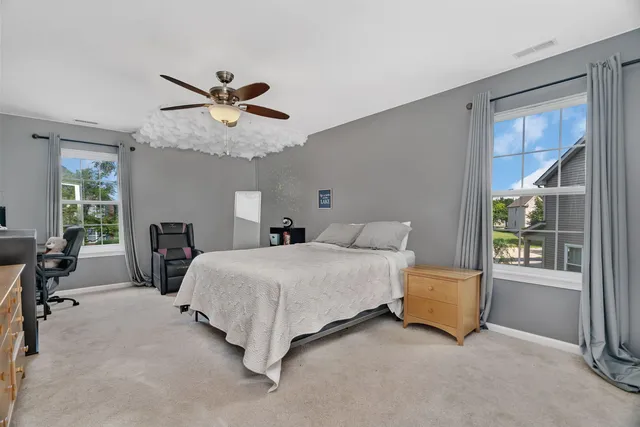 a spacious bedroom with a bed a chandelier and windows