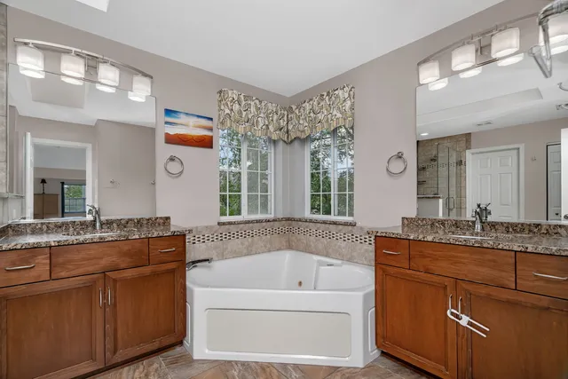 a bathroom with a granite countertop tub sink and mirror