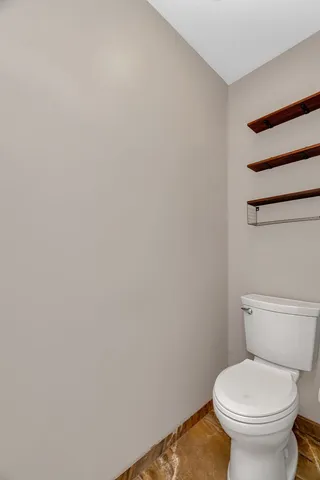 a white toilet sitting next to a white wall