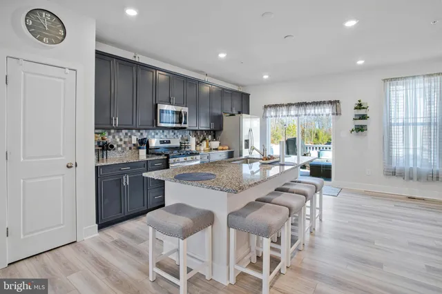 a kitchen with stainless steel appliances granite countertop a stove top oven a sink dishwasher and a refrigerator with wooden floor