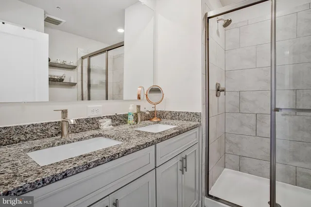 a bathroom with a granite countertop sink a mirror and shower
