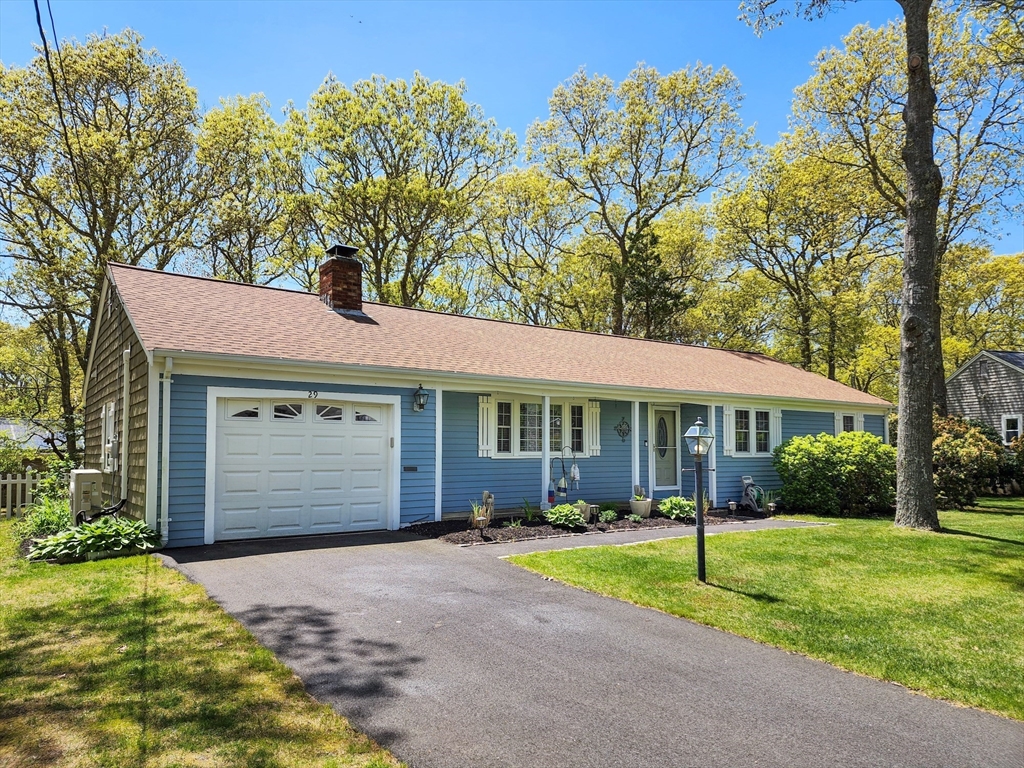 a front view of a house with a garden and trees