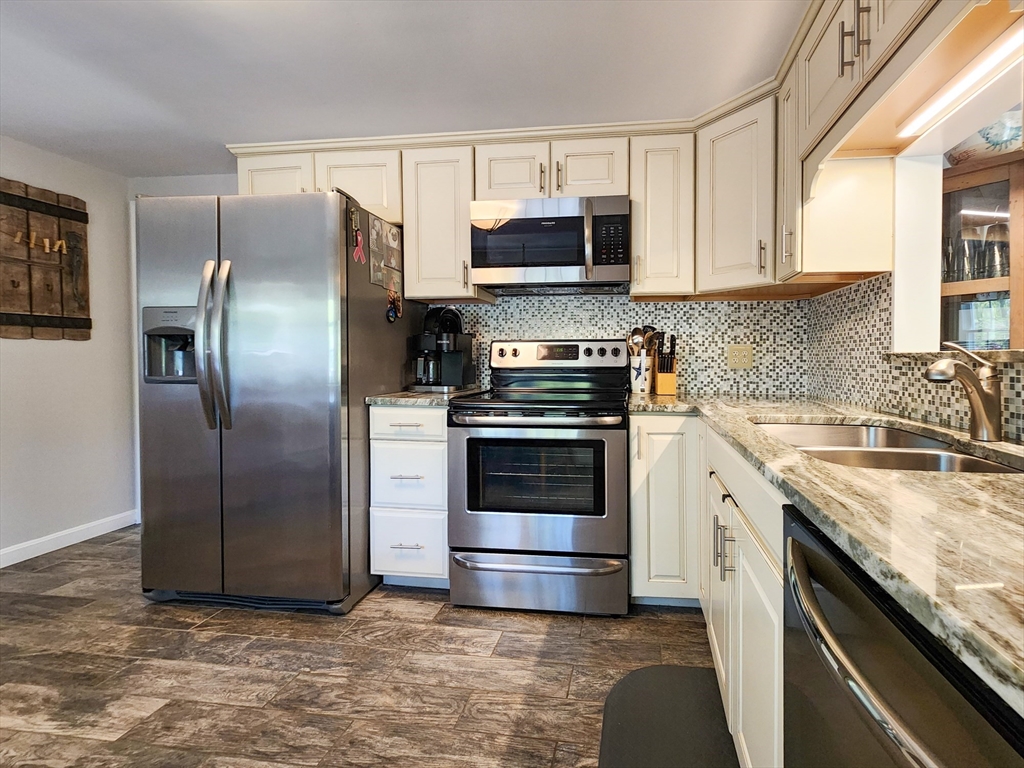 29 Sullivan Road Yarmouth, MA 02673 - Photo 7 of 42 a kitchen with stainless steel appliances granite countertop a refrigerator a microwave a sink and white cabinets