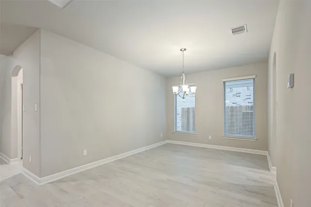 an empty room with chandelier fan and windows