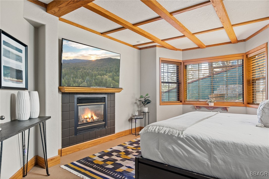 28971 Banff Drive Lake Arrowhead, CA 92352 - Photo 13 of 46 a bedroom with a bed a fireplace and a flat tv screen next to a window