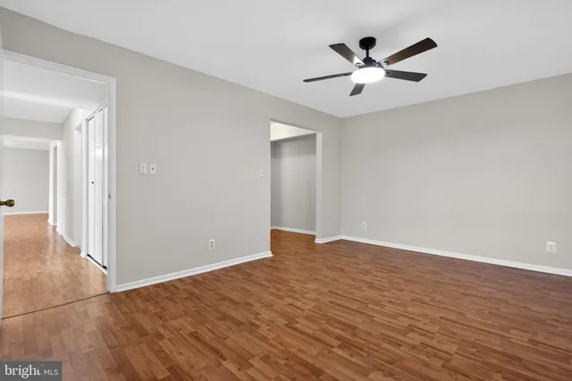 an empty room with wooden floor and ceiling fan