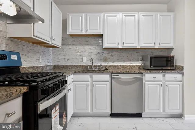 a kitchen with white cabinets and black appliances
