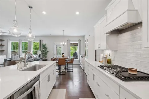 a kitchen with stainless steel appliances a stove a sink a oven a dining table and chairs