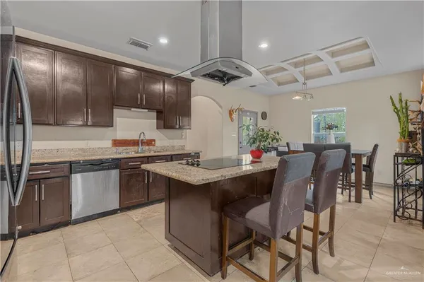 a kitchen with granite countertop stainless steel appliances a sink counter space and a view of living room
