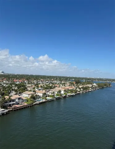 an aerial view of ocean and residential houses with outdoor space
