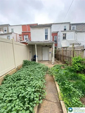 a front view of a house with a garden and trees