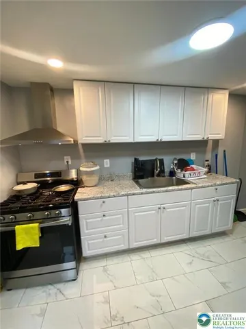 a kitchen with granite countertop a stove top oven sink and cabinets