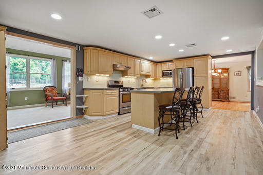 77 Tennent Road Morganville, NJ 07751 - Photo 8 of 37 a kitchen with stainless steel appliances granite countertop a stove top oven a sink dishwasher a dining table and chairs with wooden floor