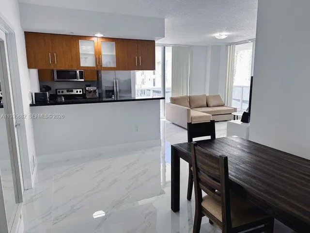 a kitchen with a table chairs refrigerator and window