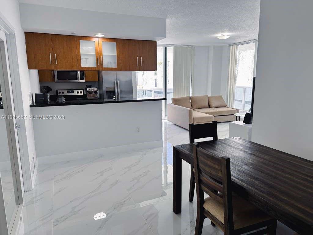 601 Northeast 23rd Street, Unit 706 Miami, FL 33137 - Photo 13 of 25 a kitchen with a table chairs refrigerator and window