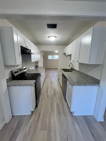 a kitchen with stainless steel appliances granite countertop wooden cabinets a sink dishwasher a stove and a refrigerator