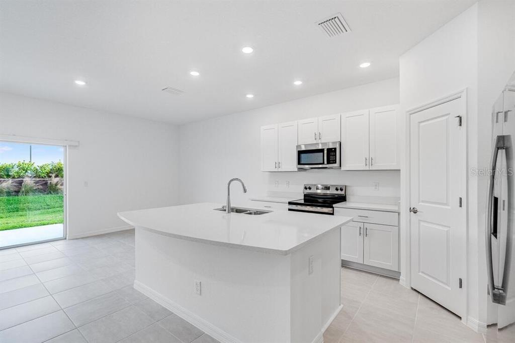3035 Novara Lane Lakewood Ranch, FL 34211 - Photo 3 of 18 a kitchen with a sink stainless steel appliances and white cabinets