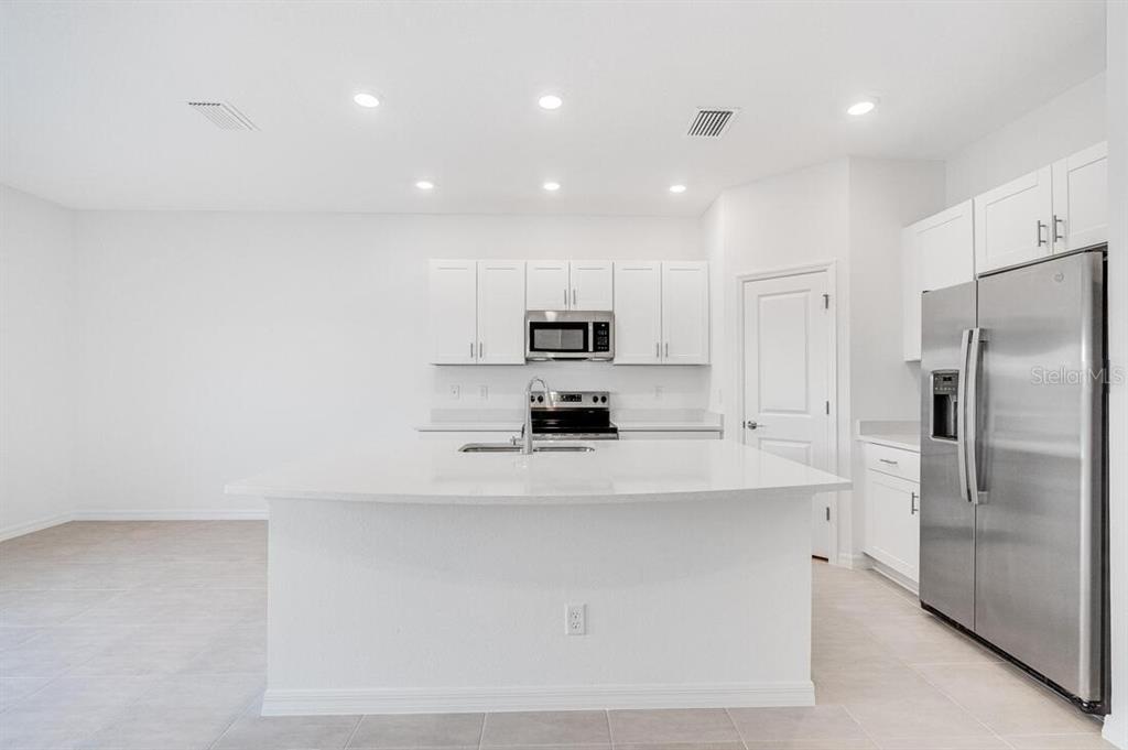 3035 Novara Lane Lakewood Ranch, FL 34211 - Photo 4 of 18 a kitchen with kitchen island a counter top space stainless steel appliances and cabinets