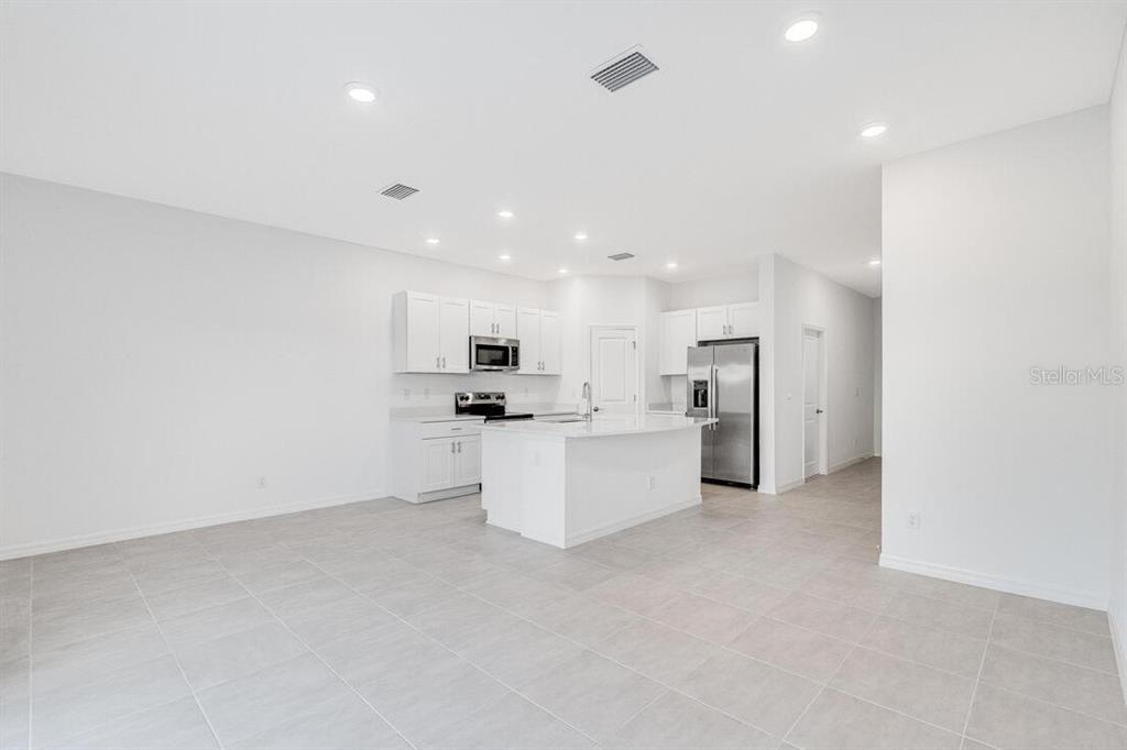 3035 Novara Lane Lakewood Ranch, FL 34211 - Photo 6 of 18 a large white kitchen with kitchen island a sink a center island stainless steel appliances and a refrigerator
