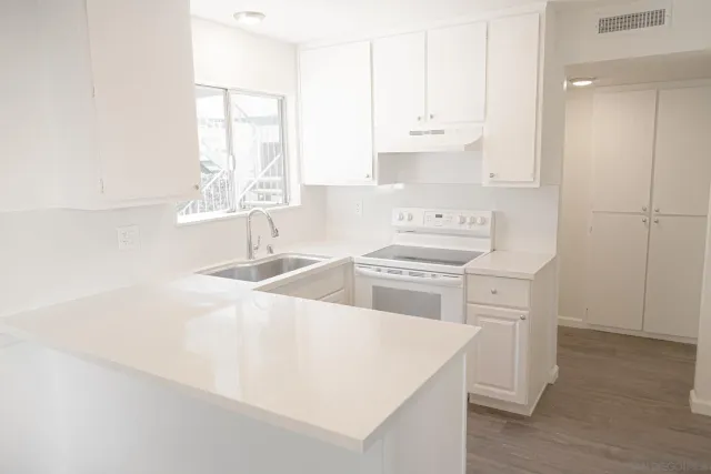 a kitchen with stainless steel appliances a sink a stove and white cabinets