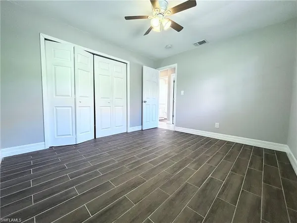 an empty room with wooden floor fan and windows