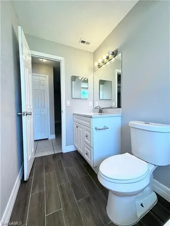 a bathroom with a toilet a sink a mirror and vanity