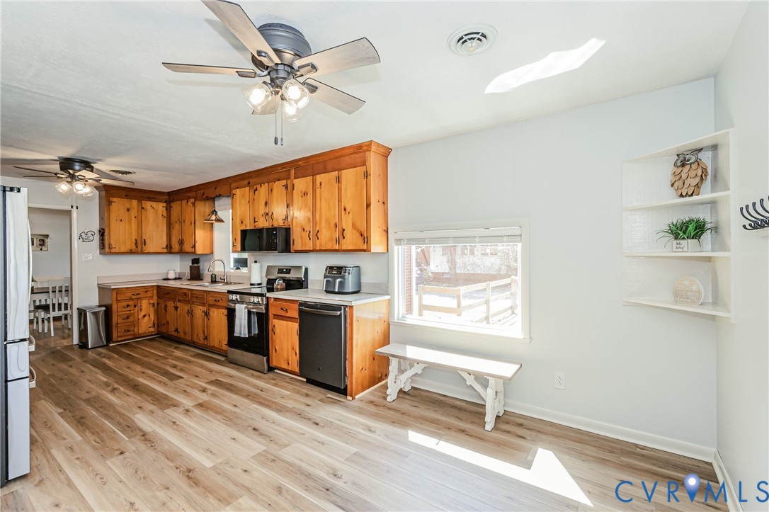 1927 F Street West Point, VA 23181 - Photo 16 of 59 a kitchen with stainless steel appliances kitchen island granite countertop a stove a refrigerator a sink a dining table and chairs with wooden floor