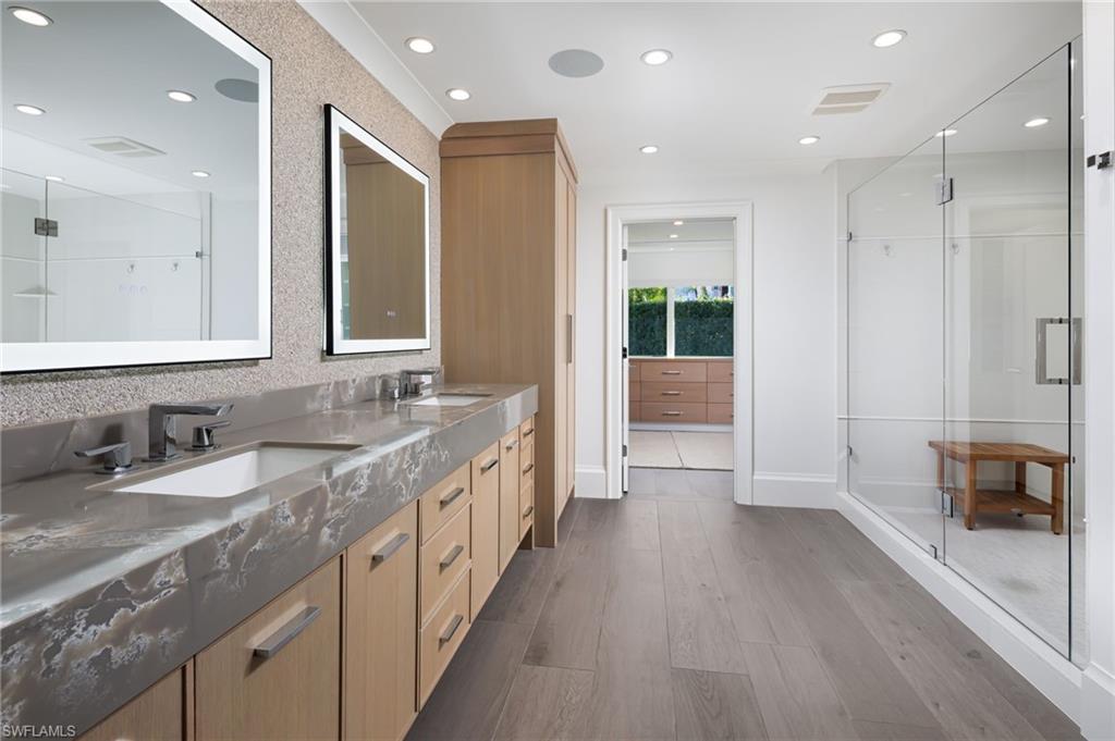 512 Neapolitan Lane Naples, FL 34103 - Photo 16 of 35 a bathroom with a granite countertop sink a large mirror and a shower