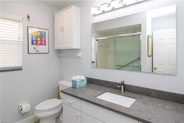 a bathroom with a granite countertop sink mirror vanity and toilet