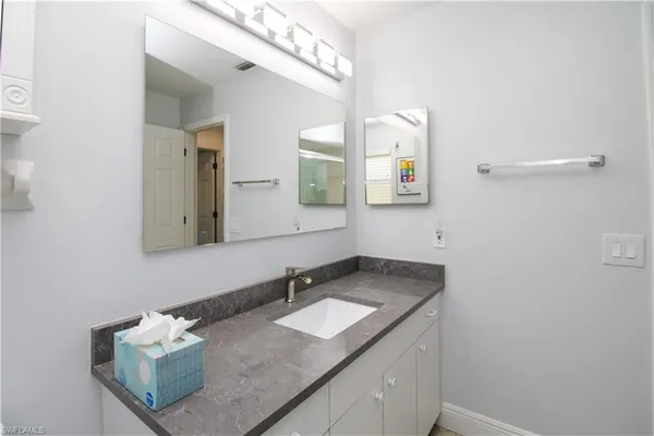 a bathroom with a granite countertop sink and a mirror