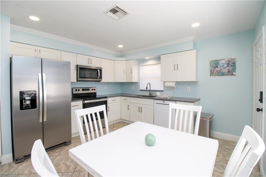 516 Gordonia Road Naples, FL 34108 - Photo 39 of 50 a kitchen with a sink a microwave a refrigerator and cabinets