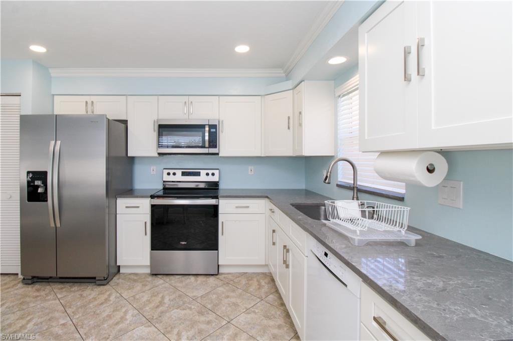 516 Gordonia Road Naples, FL 34108 - Photo 40 of 50 a kitchen with stainless steel appliances granite countertop a sink a stove a refrigerator and a microwave