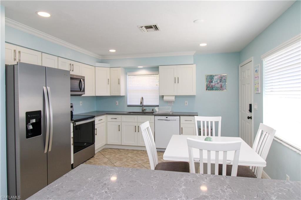 516 Gordonia Road Naples, FL 34108 - Photo 4 of 50 a kitchen with stainless steel appliances granite countertop a refrigerator a sink a stove a dining table and chairs