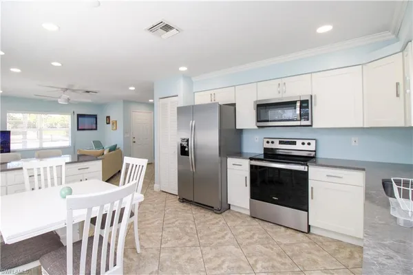 a kitchen with stainless steel appliances granite countertop a refrigerator a stove a microwave oven a sink with island and chairs