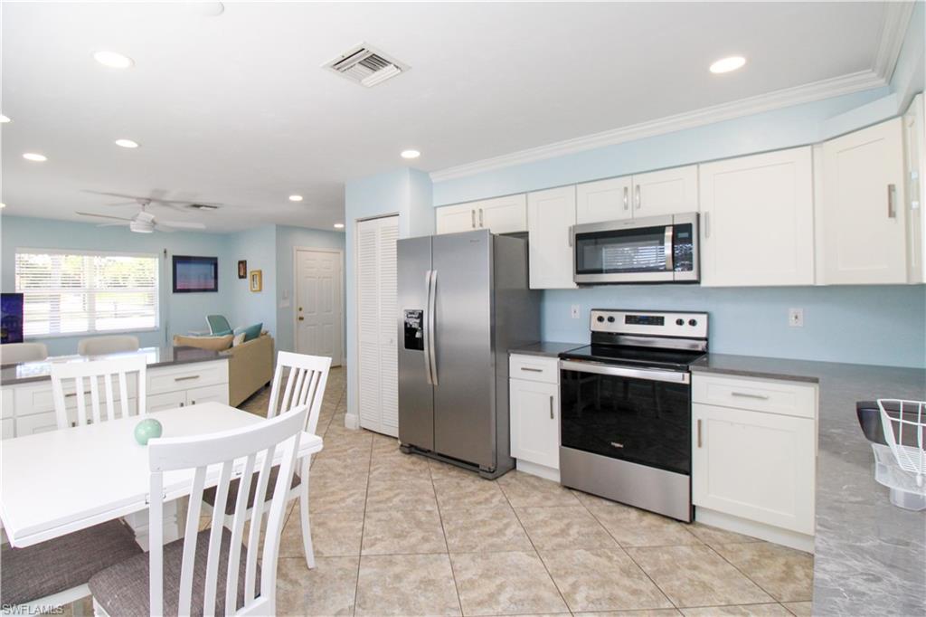 516 Gordonia Road Naples, FL 34108 - Photo 41 of 50 a kitchen with stainless steel appliances granite countertop a refrigerator a stove a microwave oven a sink with island and chairs