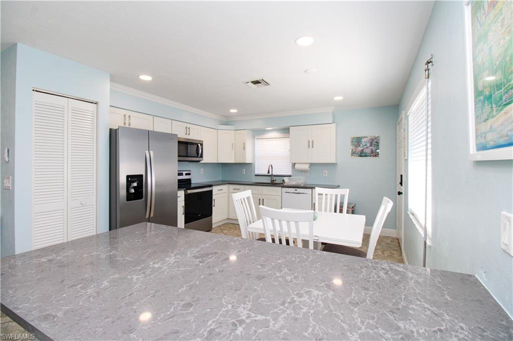 516 Gordonia Road Naples, FL 34108 - Photo 45 of 50 a large white kitchen with white cabinets and stainless steel appliances