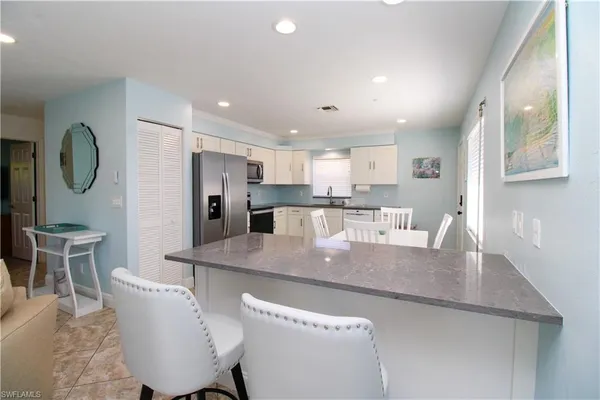 a large kitchen with stainless steel appliances granite countertop a table chairs in it and a window