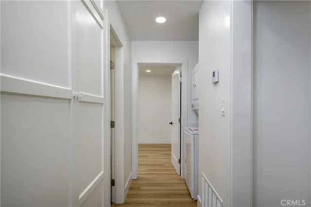 a view of a hallway with wooden floor and a bathroom