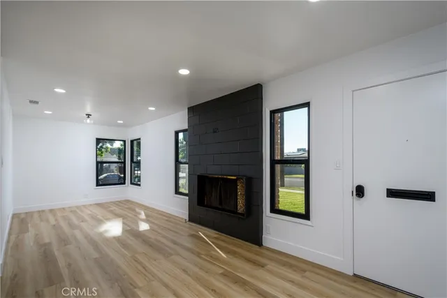 a view of an empty room with wooden floor fireplace and a window