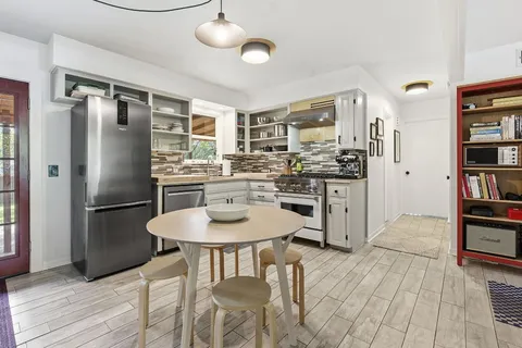 a kitchen with stainless steel appliances granite countertop a dining table chairs refrigerator and cabinets