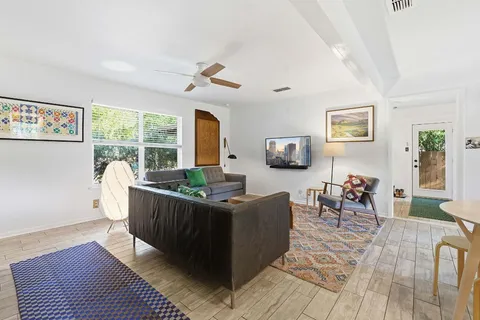 a living room with furniture a large window and wooden floor