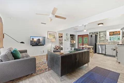 a living room with furniture kitchen view and a large window