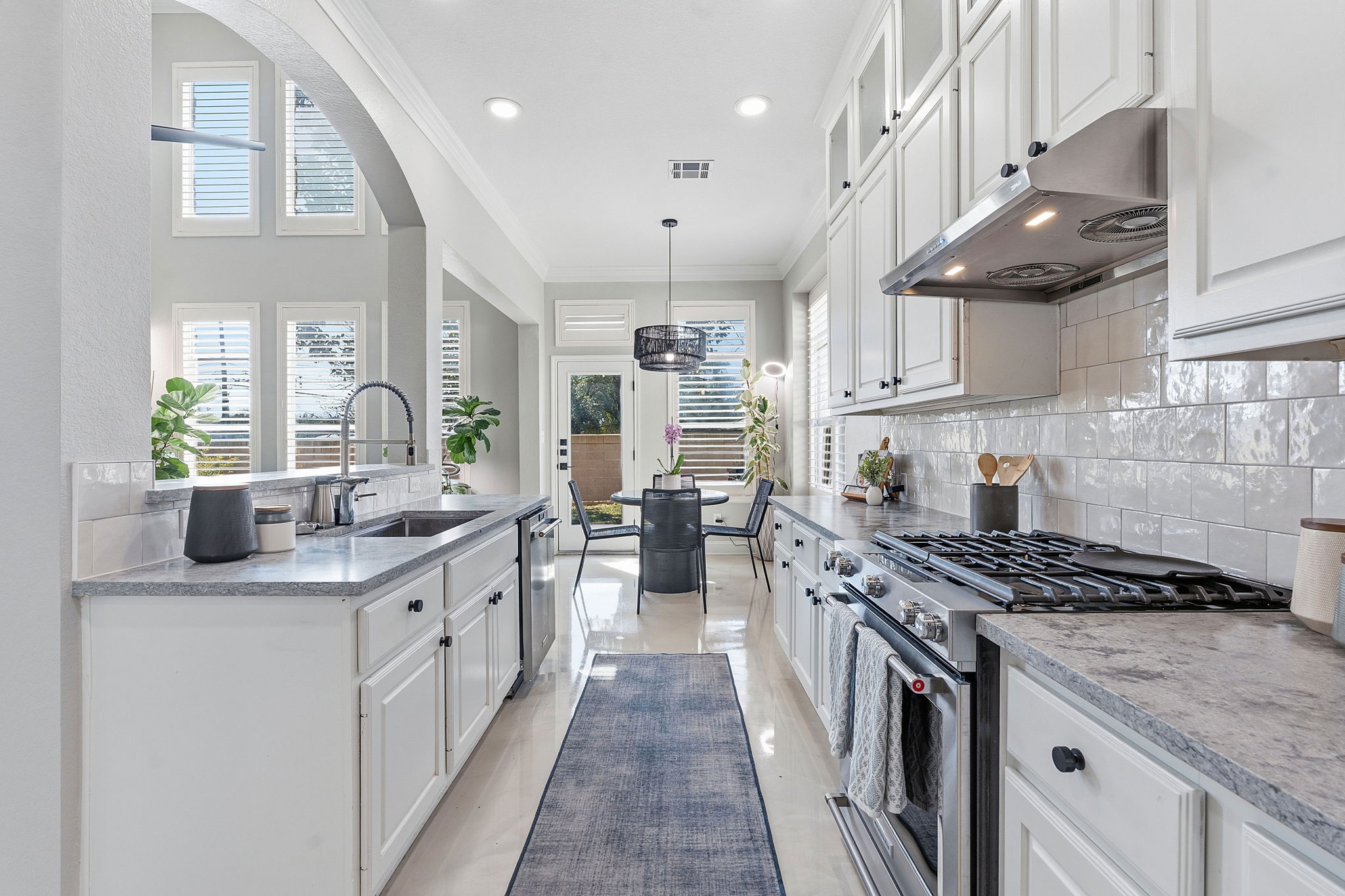 Kitchen featuring white cabinetry, stainless steel appliances, ornamental molding, glass fronted cabinets, and tasteful backsplash