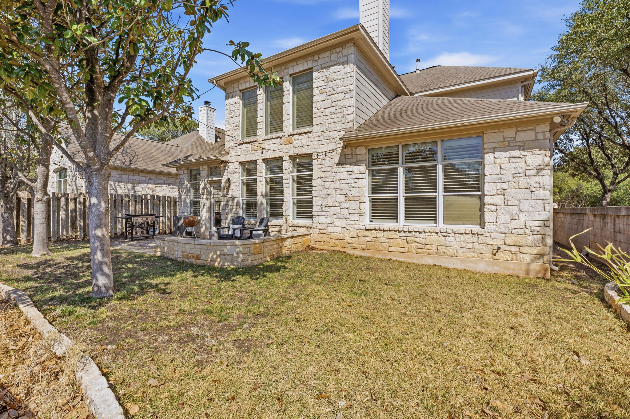 5000 Mission Oaks Boulevard, Unit 30 Austin, TX 78735 - Photo 25 of 31 Back of house featuring stone siding, a fenced backyard, and a patio.5000 Mission Oaks Dr #30