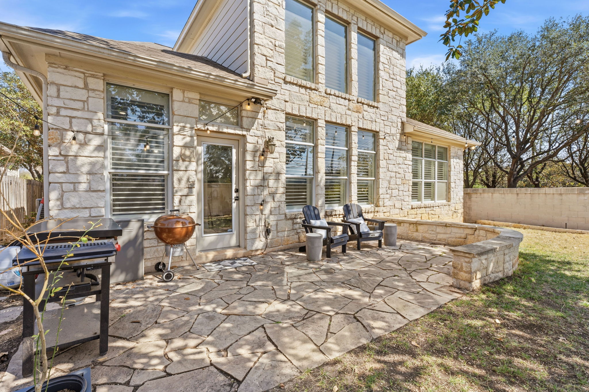 5000 Mission Oaks Boulevard, Unit 30 Austin, TX 78735 - Photo 26 of 31 Back of house featuring stone siding, a fenced backyard, and a patio.5000 Mission Oaks Dr #30