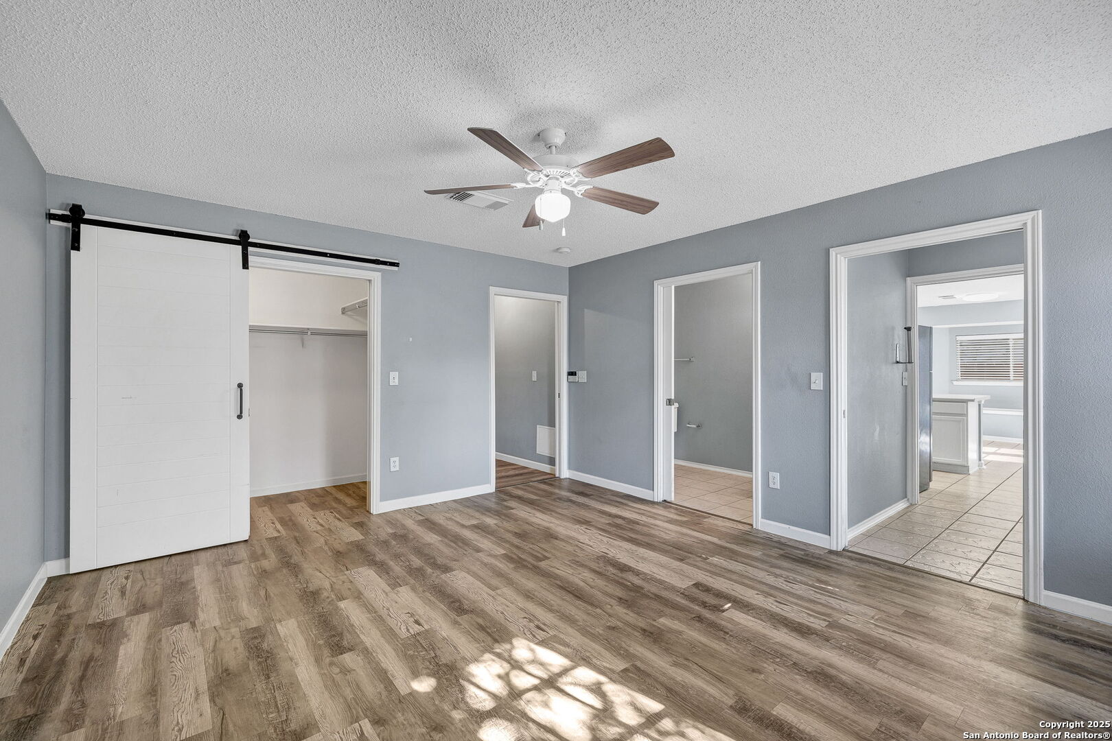 7362 Rustling Brook San Antonio, TX 78249 - Photo 18 of 36 a view of a big room with wooden floor and a ceiling fan